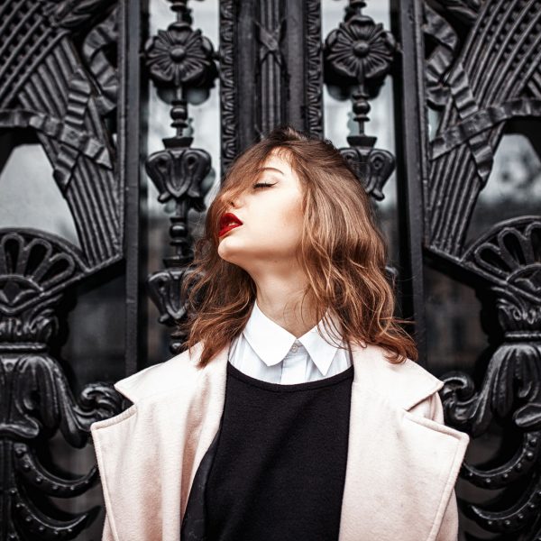 Vintage Street fashion photo. Beautiful young woman in oversize Vintage Street fashion photo. Beautiful young woman in oversize coat and wavy hair outside.